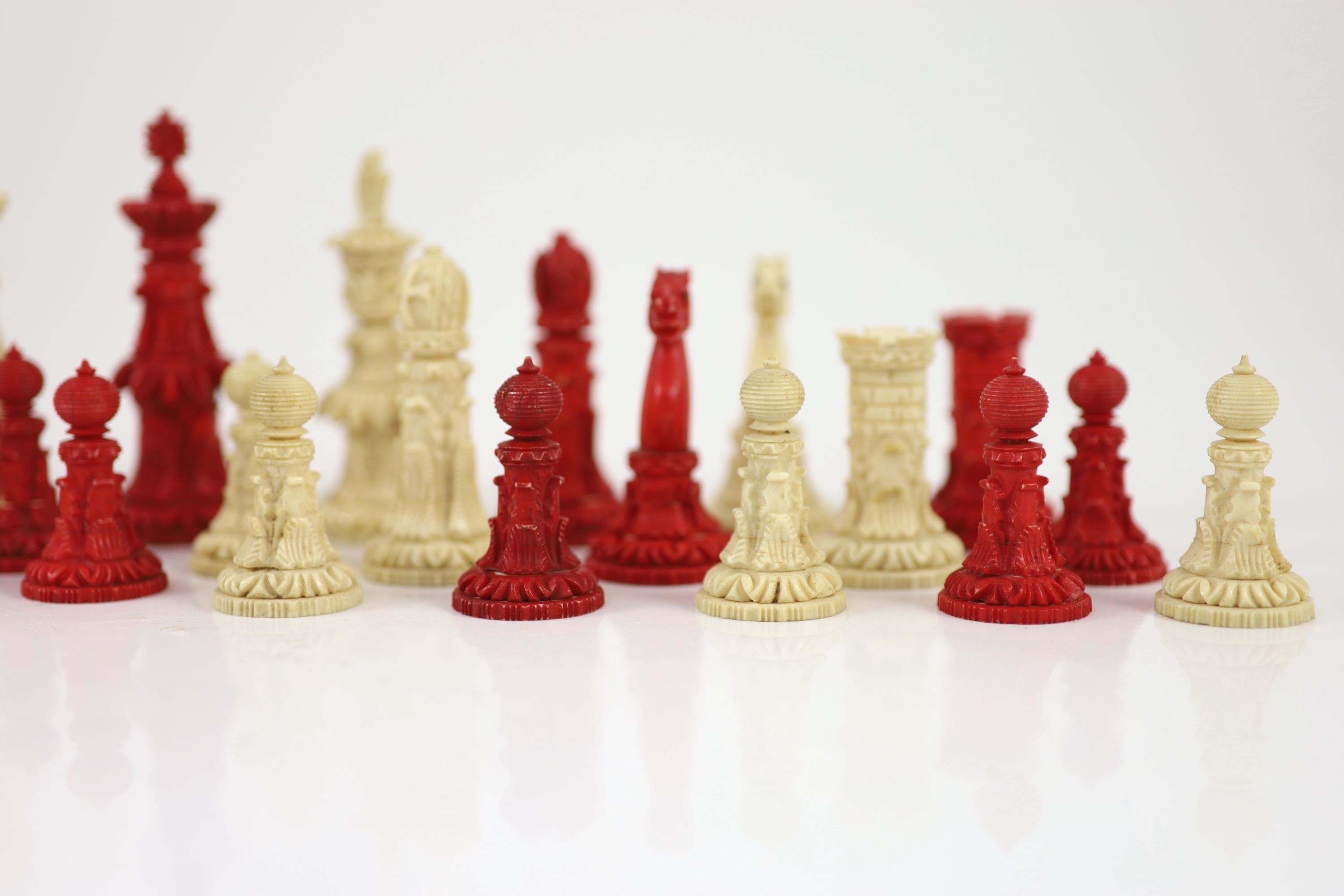 A 19th century Anglo-Indian white and stained bone chess set, with unusual carved palmate decoration, Kings 9.5cm.